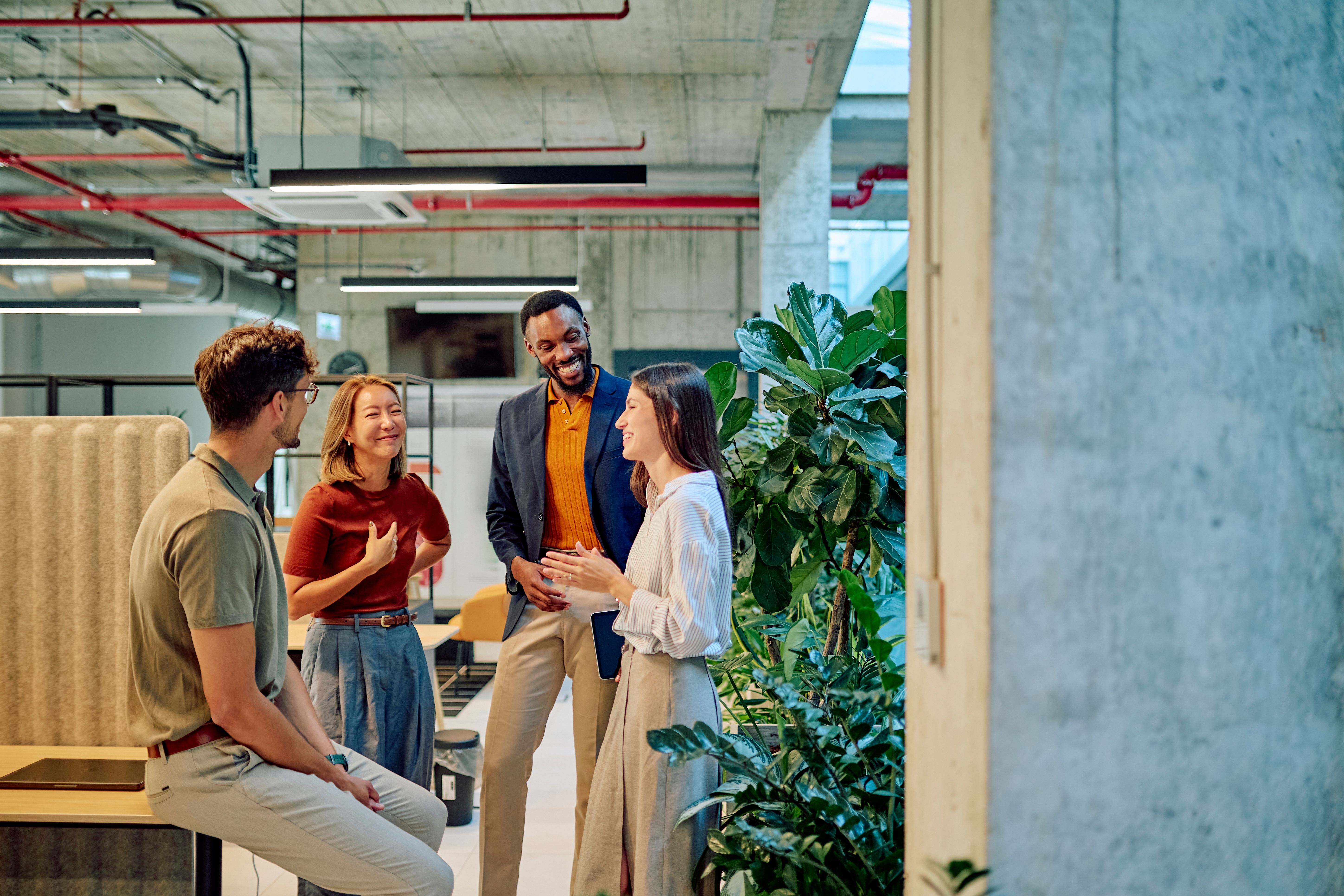 Multicultural businesspeople talking and smiling during a meeting in a modern office with plants